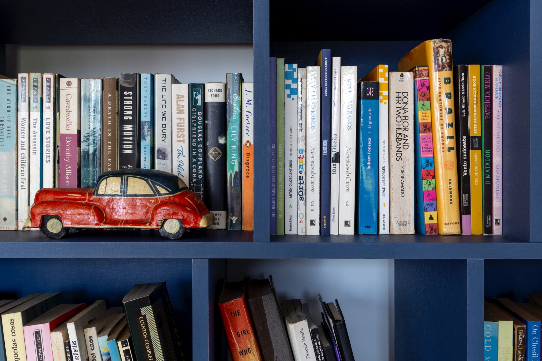 Detalhe de estante azul com livros e objeto decorativo